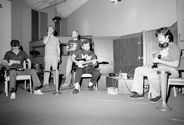 Jim Blake smokes a joint while musicians prepare for a recording session, 1970s. - PAT RAINER